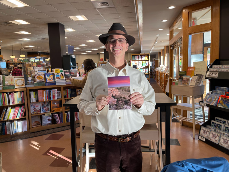 Author stan finger standing in a bookstore and holding a copy of 105 Meadowlark Reader (Issue #6)